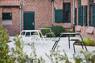 Playful outdoor setting with colorful Virus tables inviting children and adults to sit together in a cheerful holiday-house garden.