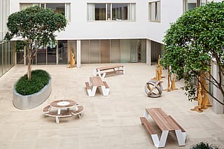 Sitzbereich im Wintergarten des Krankenhauses mit einem Hopper-Picknicktisch in einem lichtdurchfluteten Innengarten, der für ruhige Pausen und informelle Gespräche konzipiert ist.