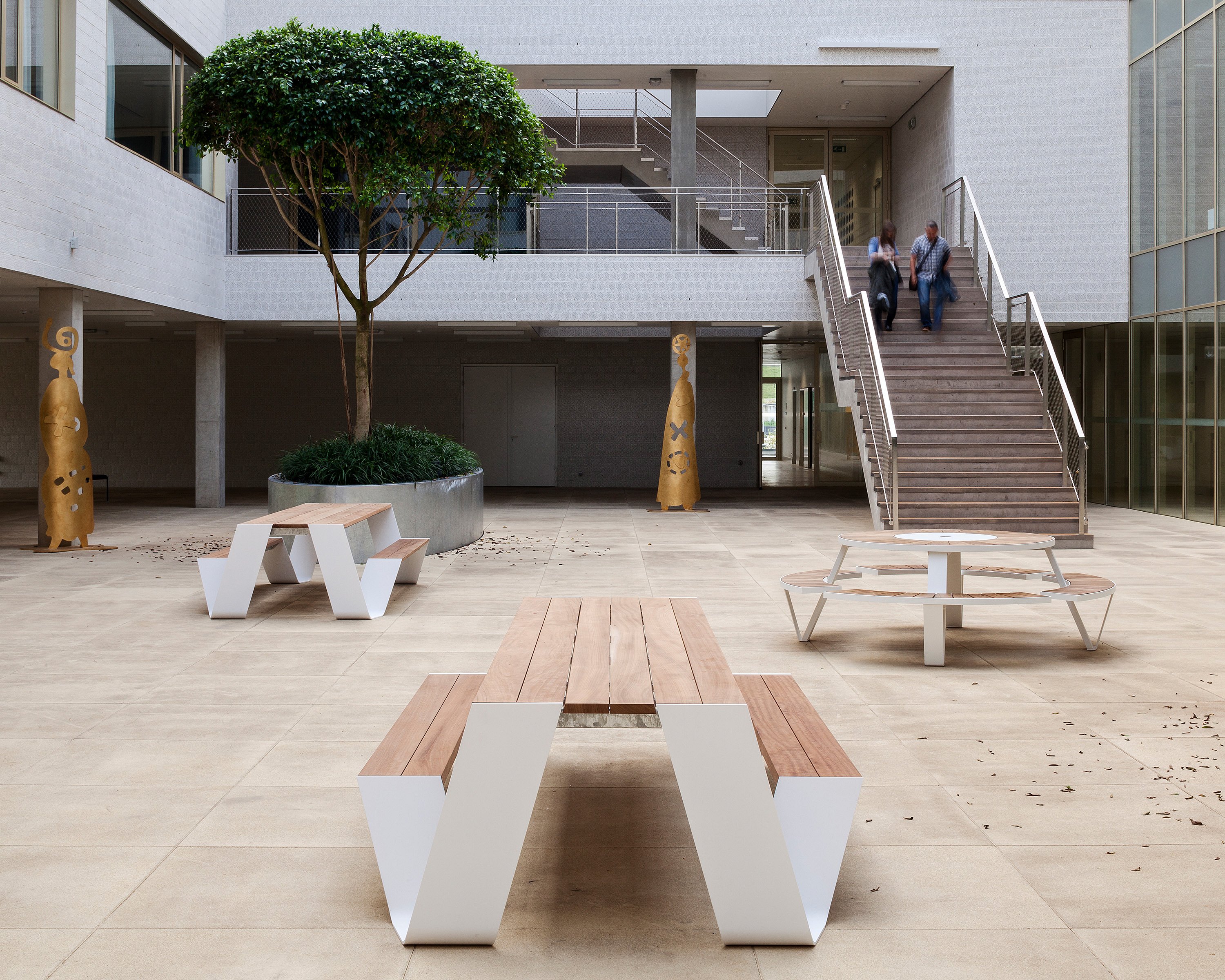 Ruhiger Indoor-Krankenhausgarten mit gemeinsamen Sitzgelegenheiten, Grün und Tageslicht, der Pflegearchitektur mit einem heimeligen Ort zum Innehalten und Verbinden kombiniert.