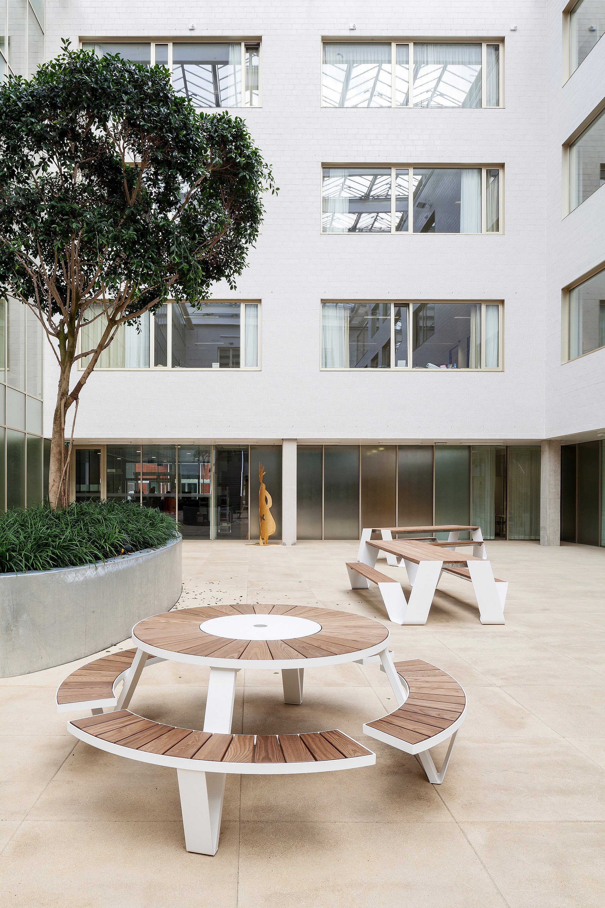 Bright hospital winter garden with Extremis outdoor-style furniture arranged among indoor planting, creating a calm shared space for patients, visitors, and caregivers.
