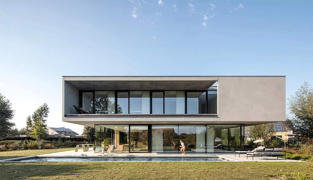 — « Villa moderne à deux étages avec de grandes parois vitrées, un étage supérieur en porte-à-faux, une pelouse et une piscine à l’avant, et des enfants visibles à l’intérieur et autour de la maison.