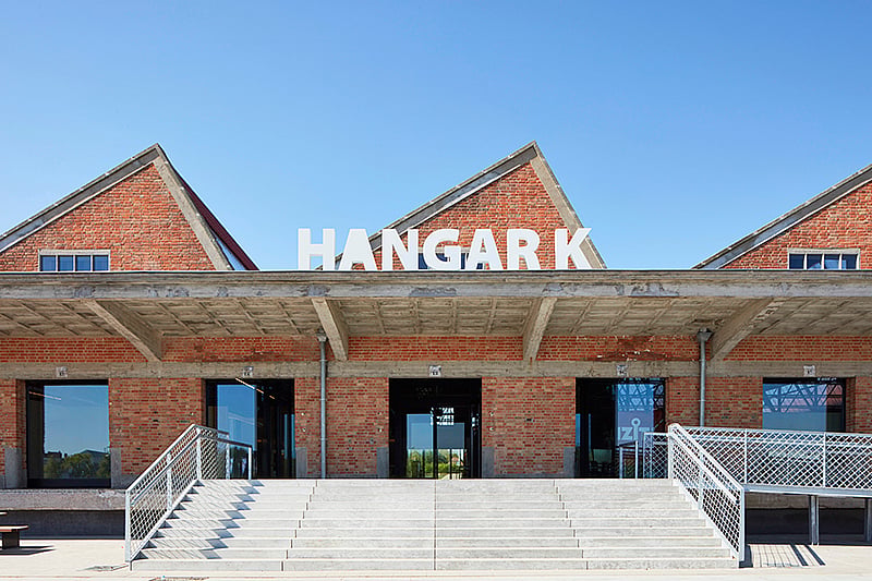 Zone d’entrée du hangar K avec une table de pique-nique Hopper et une table Anker placées dans l’espace de travail industriel ouvert, créant un endroit pour les pauses café et les réunions informelles.