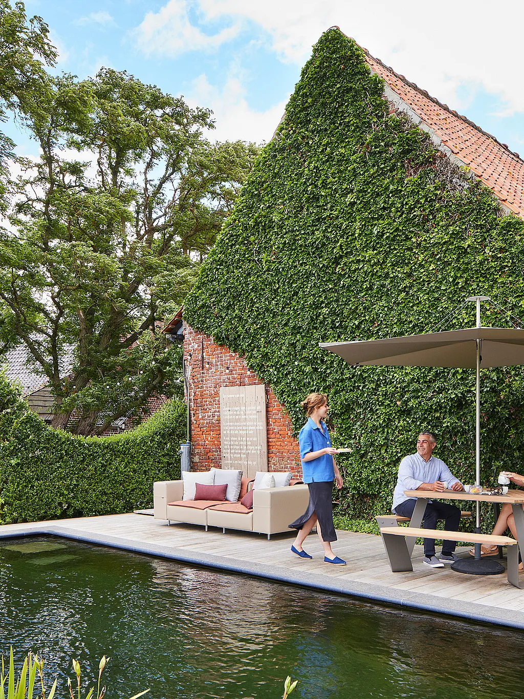 Charming cottage garden at a rural guesthouse in the Belgian countryside, with multiple outdoor seating areas creating a peaceful, inviting place to relax.