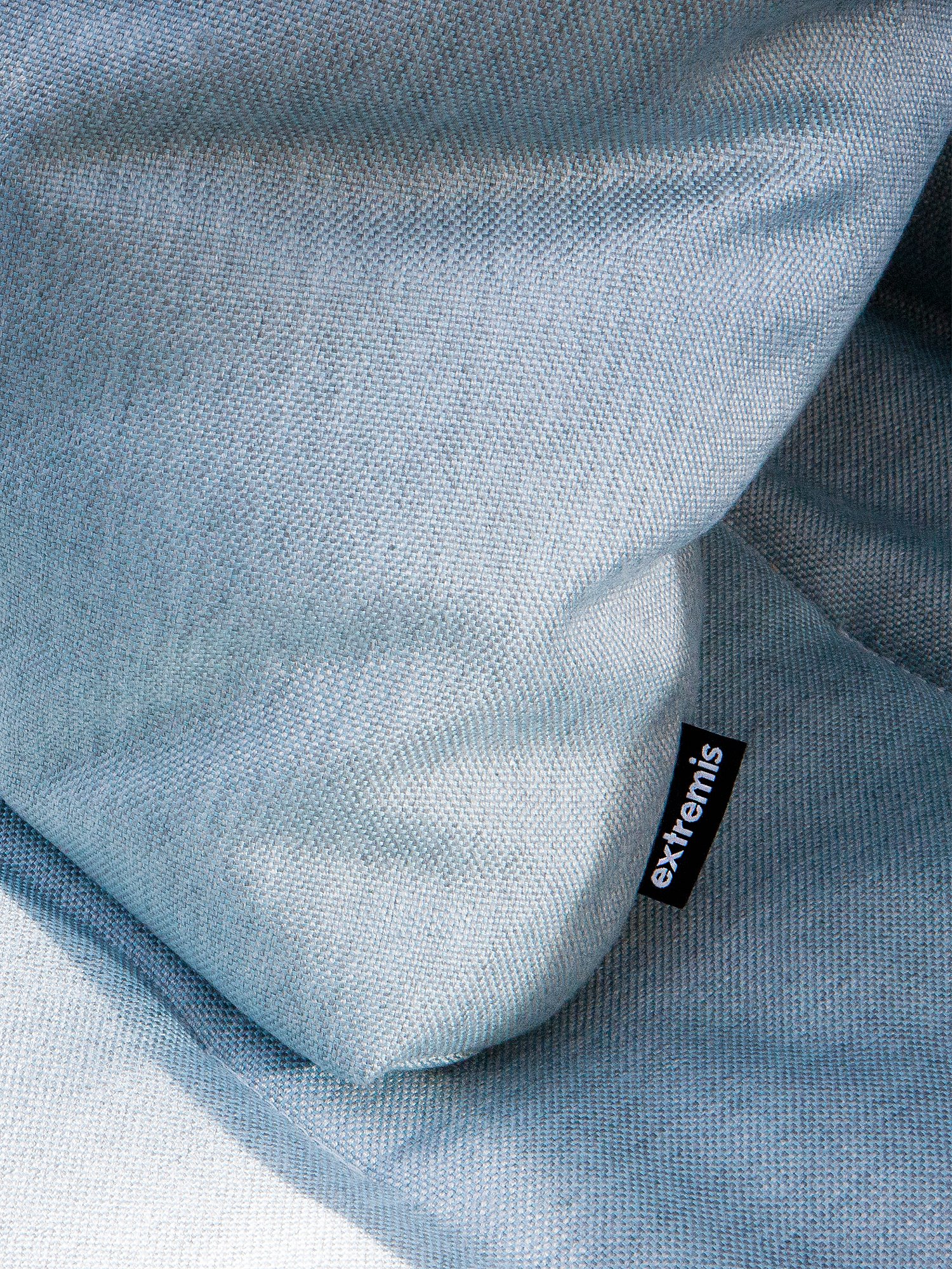 Close-up of pale blue Walrus cushions with soft folds and an Extremis fabric tag, highlighting the lounge’s tactile textile finish.