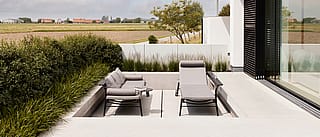Hausgartenszene mit Gartenmöbeln zum Essen und Entspannen, wobei Zusammengehörigkeit, Komfort und ruhige Zeit mit der Familie im Vordergrund stehen.