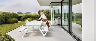 Long Marina Combo Esstisch im Freien in einem privaten Garten, der feste Bänke und einzelne Kapitänsstühle kombiniert, um Familie und Freunde zusammenzusetzen.