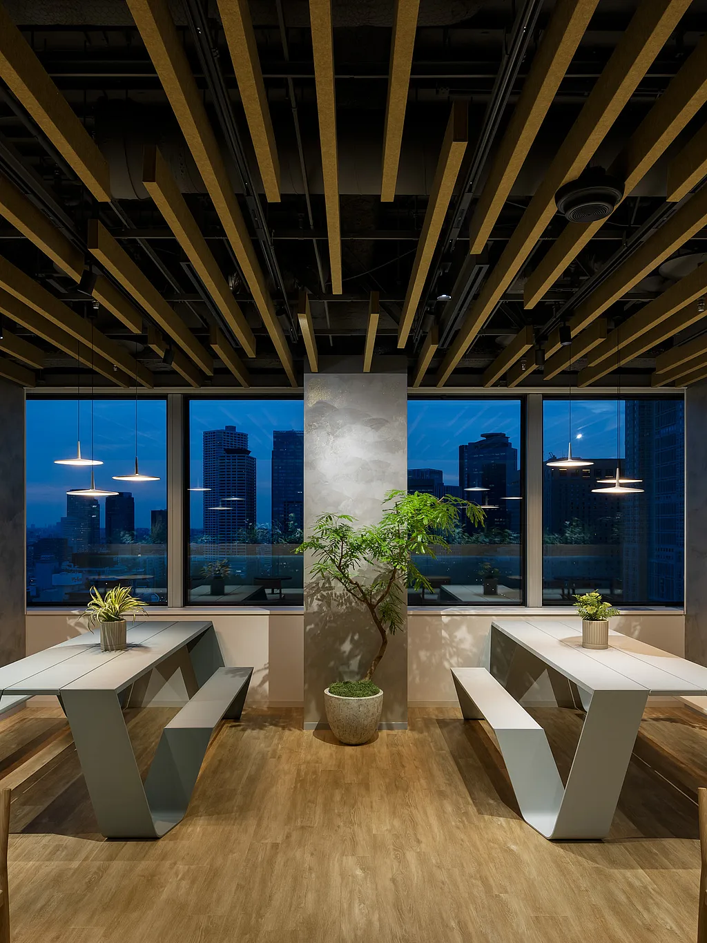 Moderne kantoorlounge met twee witte Hopper-picknicktafels, potbomen en hanglampen, tegenover grote ramen met uitzicht op de skyline van Tokio in de schemering.