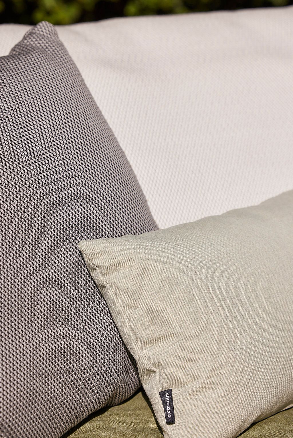 Nahaufnahme weicher Outdoor-Kissen in gedämpften Grau- und Hellgrüntönen auf dem Walrus-Sofa, wobei die strukturierten Polster- und Kissendetails hervorgehoben werden.