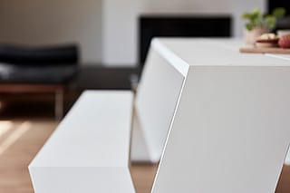 Close-up van de witte Hopper binnentafel en bank, met de nadruk op de strakke hoeklijnen van het tafelblad en de poten.
