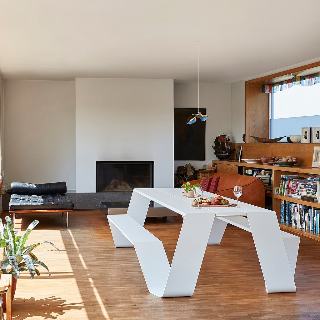 Ein weißer Hopper-Picknicktisch aus Aluminium drinnen in einem gemütlichen Wohnzimmer mit Kamin.