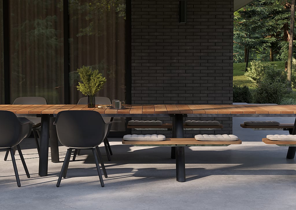 Close view of the wooden Panigiri tabletop, black Captain’s Chairs, and bench cushions on a covered patio in front of a dark brick wall.