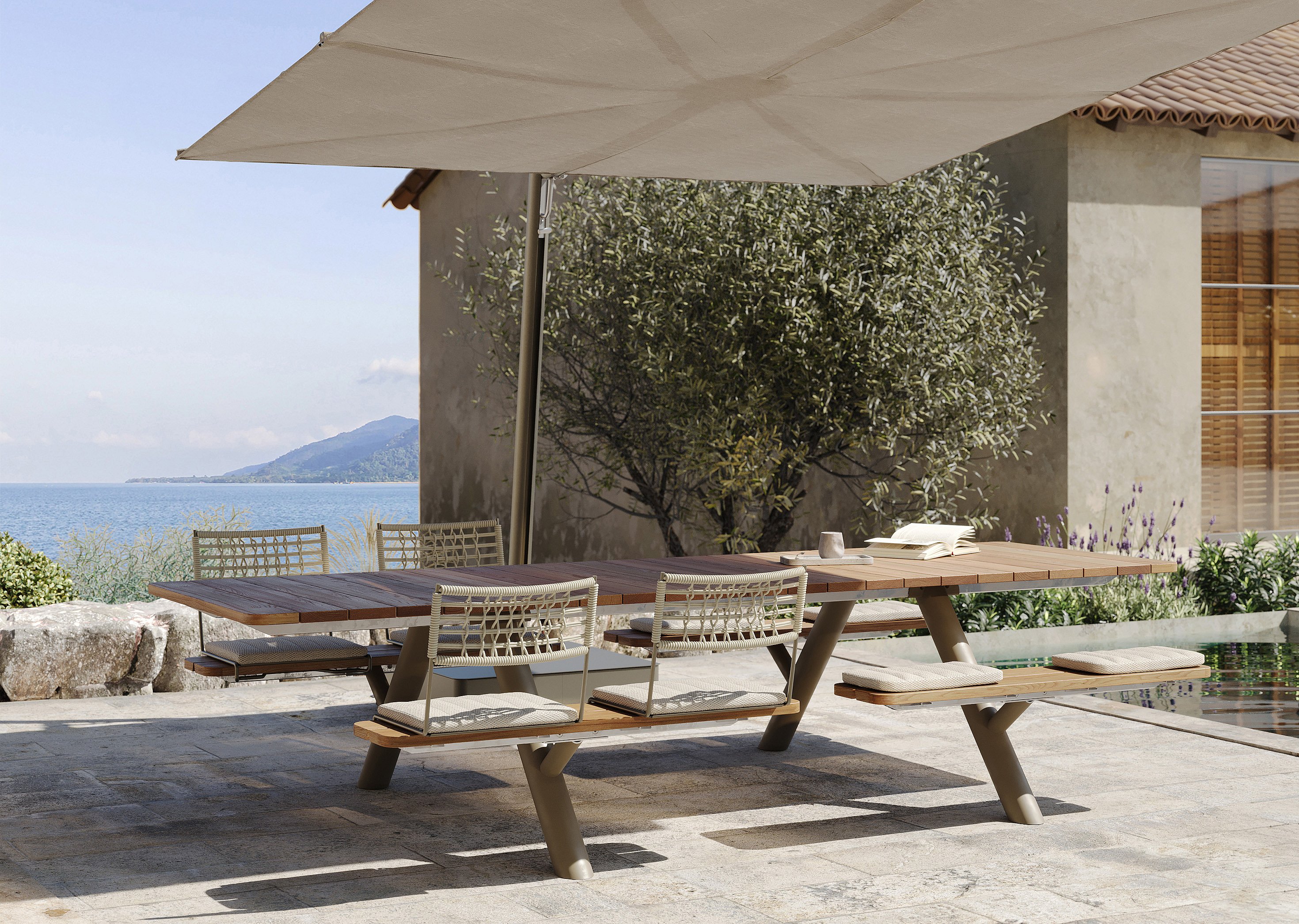 Wooden Panigiri picnic table with woven BYOS backrests and seat cushions under a large Sensu shade, overlooking the sea beside a villa terrace.