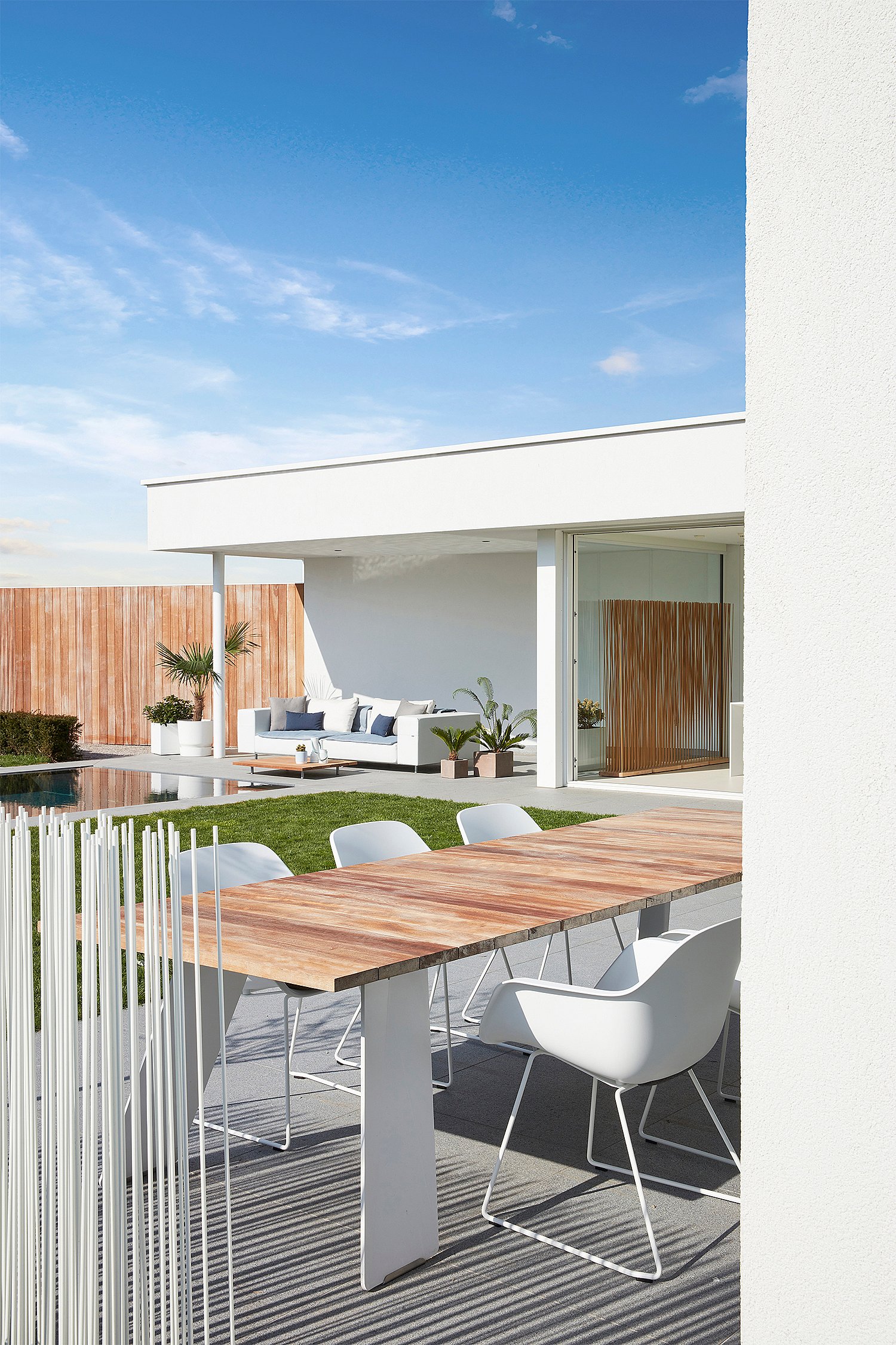 Moderner Hinterhof mit Lounge-, Ess- und Poolbereichen, konzipiert als ruhiger Rückzugsort für den Aufenthalt zu Hause mit klaren Linien und natürlichen Materialien.