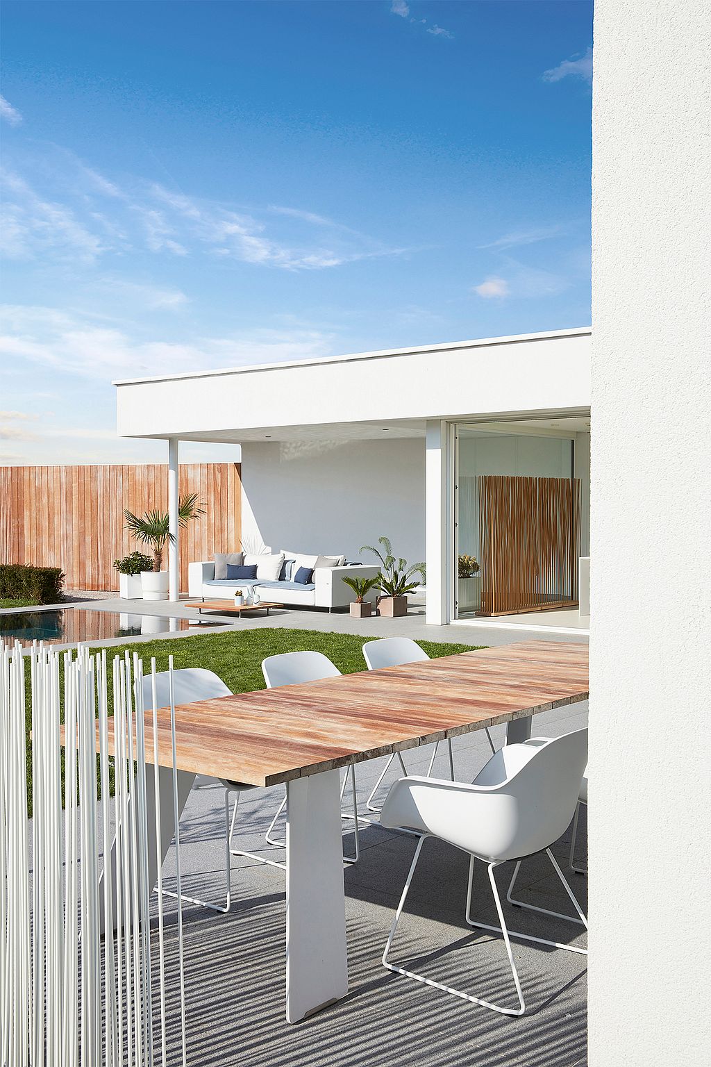 Moderner Hinterhof mit Lounge-, Ess- und Poolbereichen, konzipiert als ruhiger Rückzugsort für den Aufenthalt zu Hause mit klaren Linien und natürlichen Materialien.
