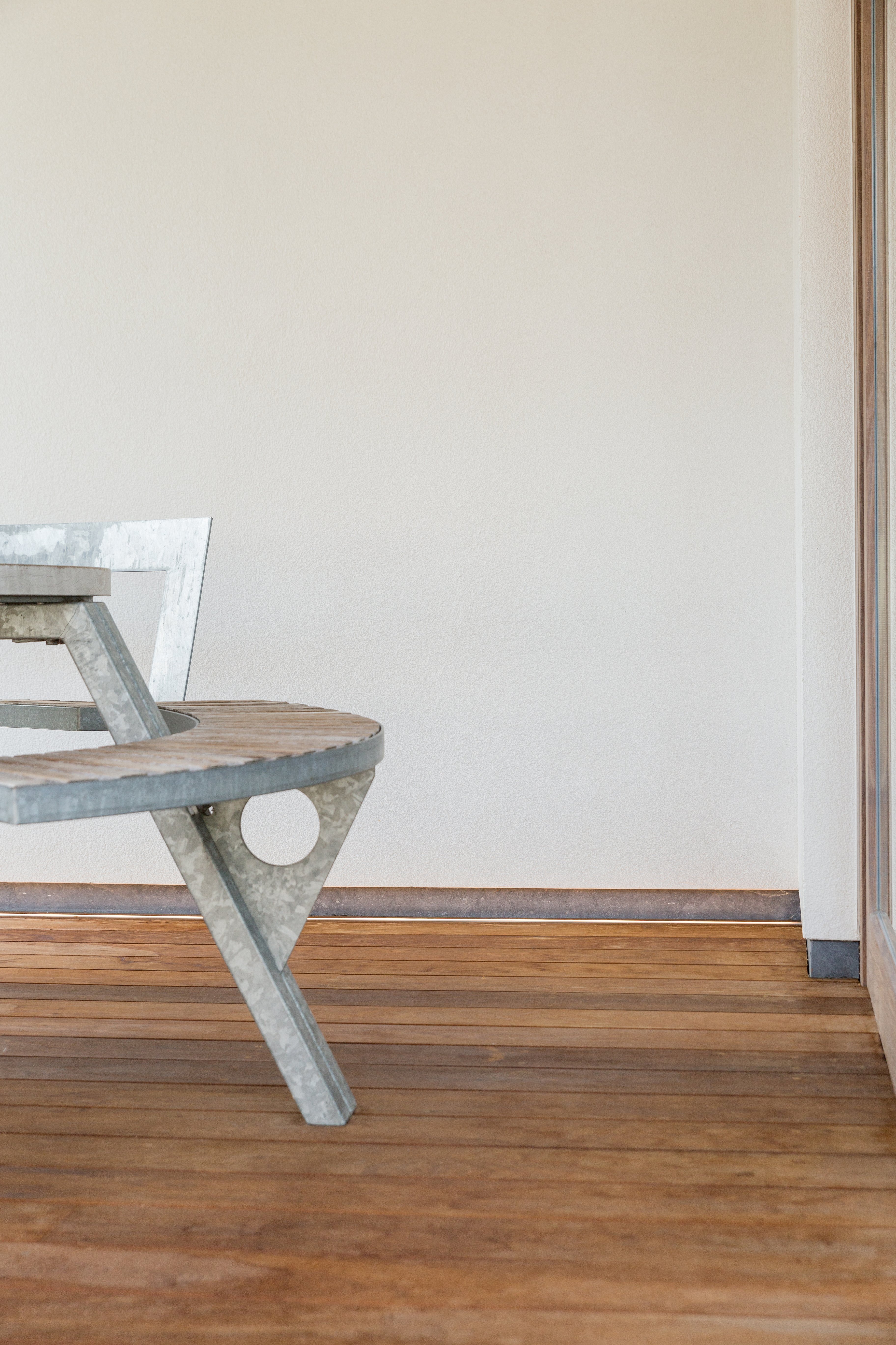 Close-up of the Gargantua table showing the galvanized steel frame, weathered wooden circular bench, and wooden terrace boards.