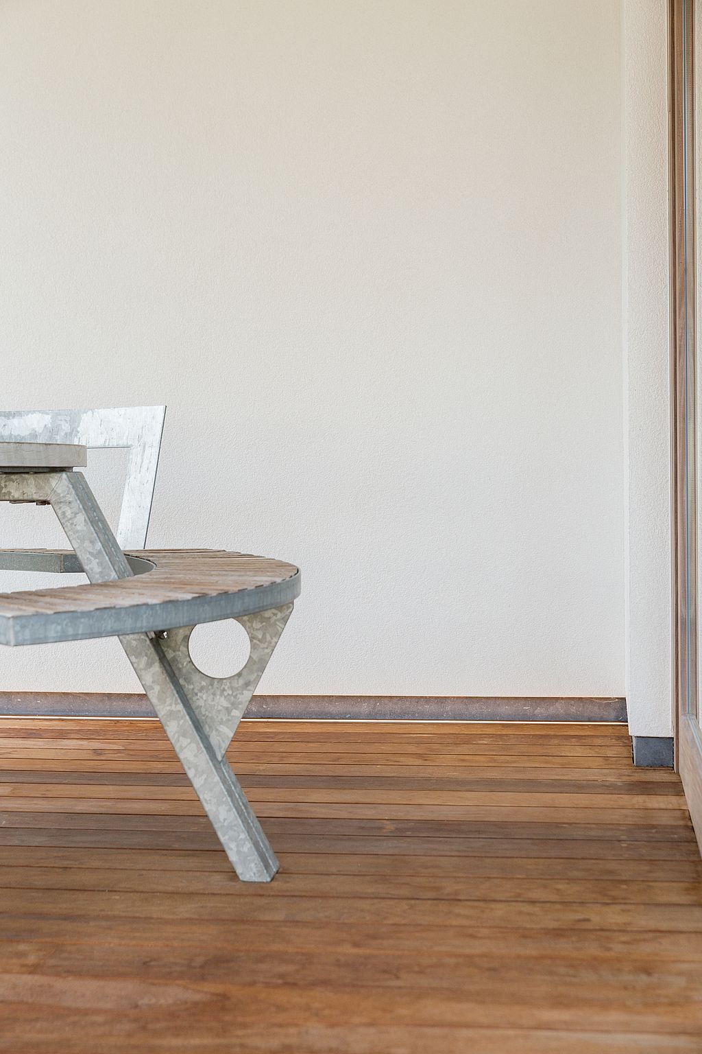 Close-up of the Gargantua table showing the galvanized steel frame, weathered wooden circular bench, and wooden terrace boards.