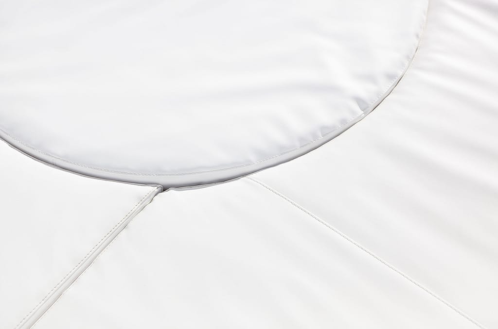 Detail van het witte ronde tafelblad en gestikte witte zitkussens, met de gladde bekleding en de gebogen vorm van de kosmos.