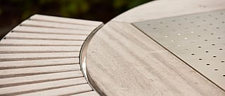 Close-up of the round wooden gargantua tabletop and slatted bench seat, showing weathered wood and a perforated metal center insert.