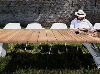 Dirk sitzt an einem Ende eines langen Pontsūn-Tisches, im Vordergrund stehen weiße Kapitänsstühle und ein Mittagessen.