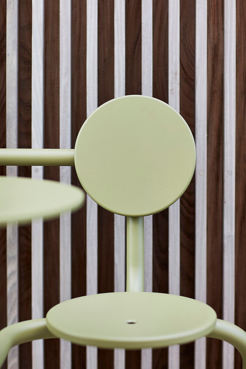 Close-up van een rietgroene Bistroo-stoel en tafelblad voor verticale houten gevelbekleding.