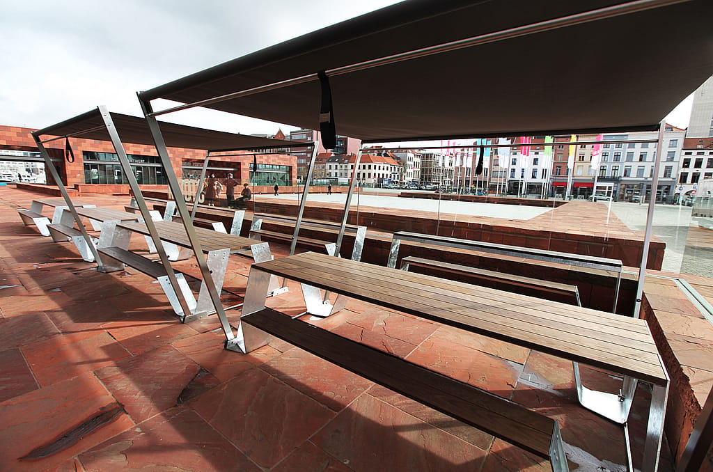 Mehrere Hopper-Picknicktische und Hopper-Bänke säumen die Caféterrasse unter dunklen Markisen mit Blick auf den offenen Platz neben dem MAS-Museum.