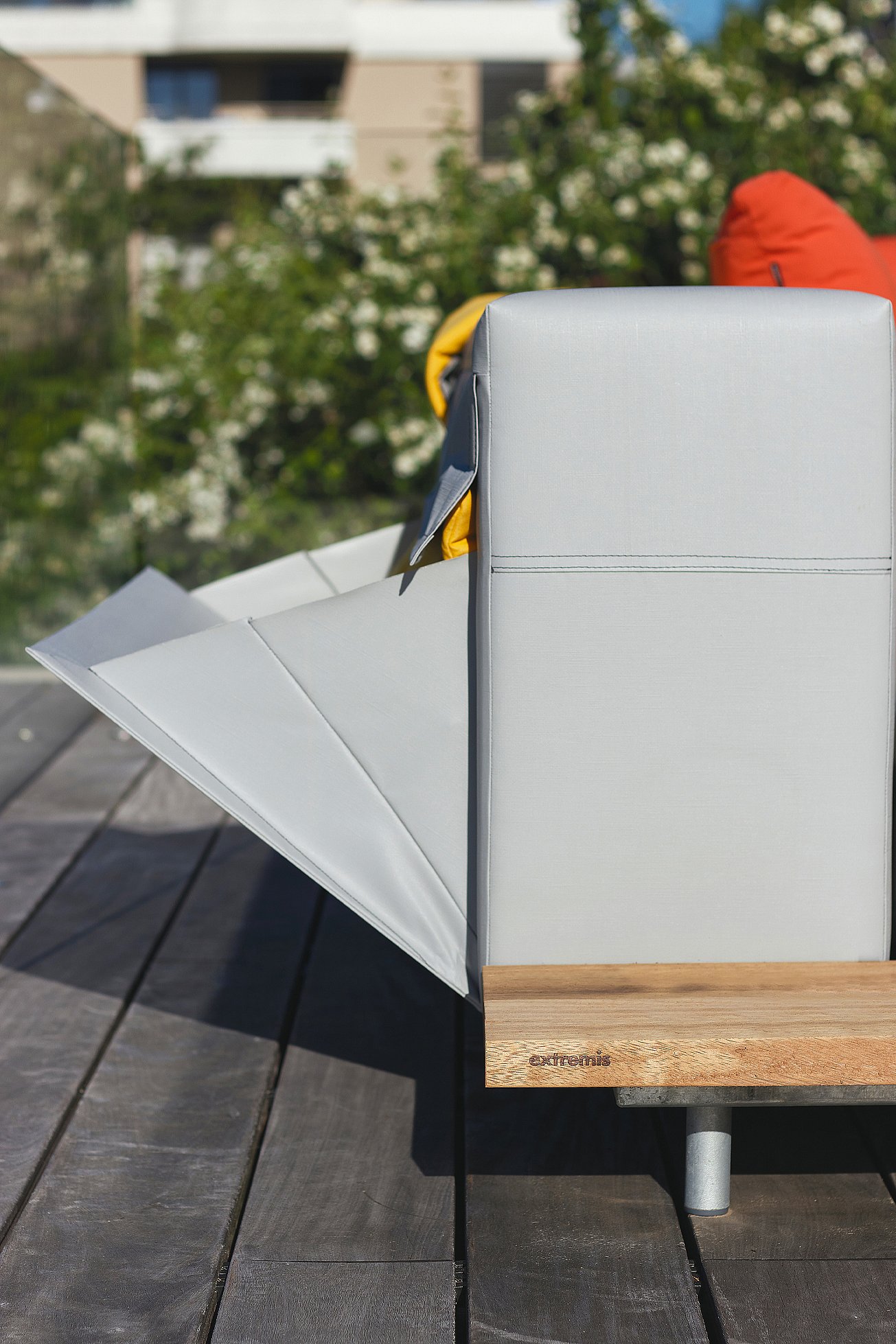Seitendetail eines grauen Walross-Sofas mit aufgeklappter Aufbewahrungsklappe, das den Holzsockel und die wetterfeste Polsterung zeigt.