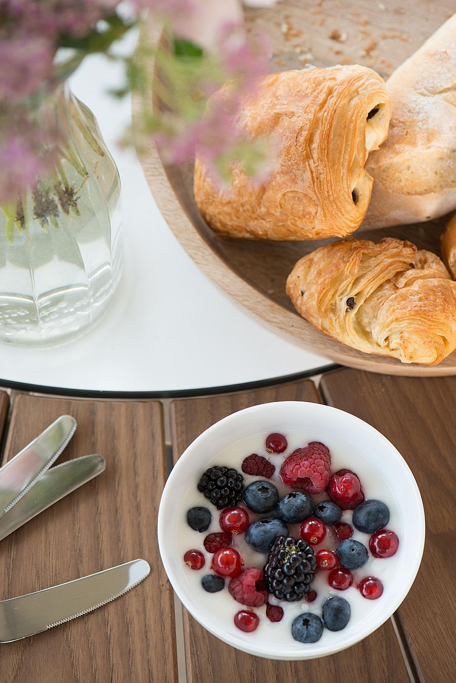 Nahaufnahme von Gebäck, Beeren und Besteck, angeordnet auf den Holzlatten und der weißen Mitte eines Pantagruel-Tisches.