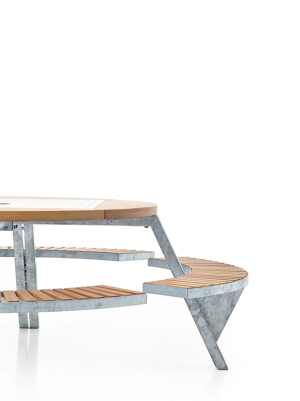 Gros plan studio de la table Gargantua montrant le plateau rond en bois, le centre en métal perforé et un banc incurvé dans une position d'assise ajustée.