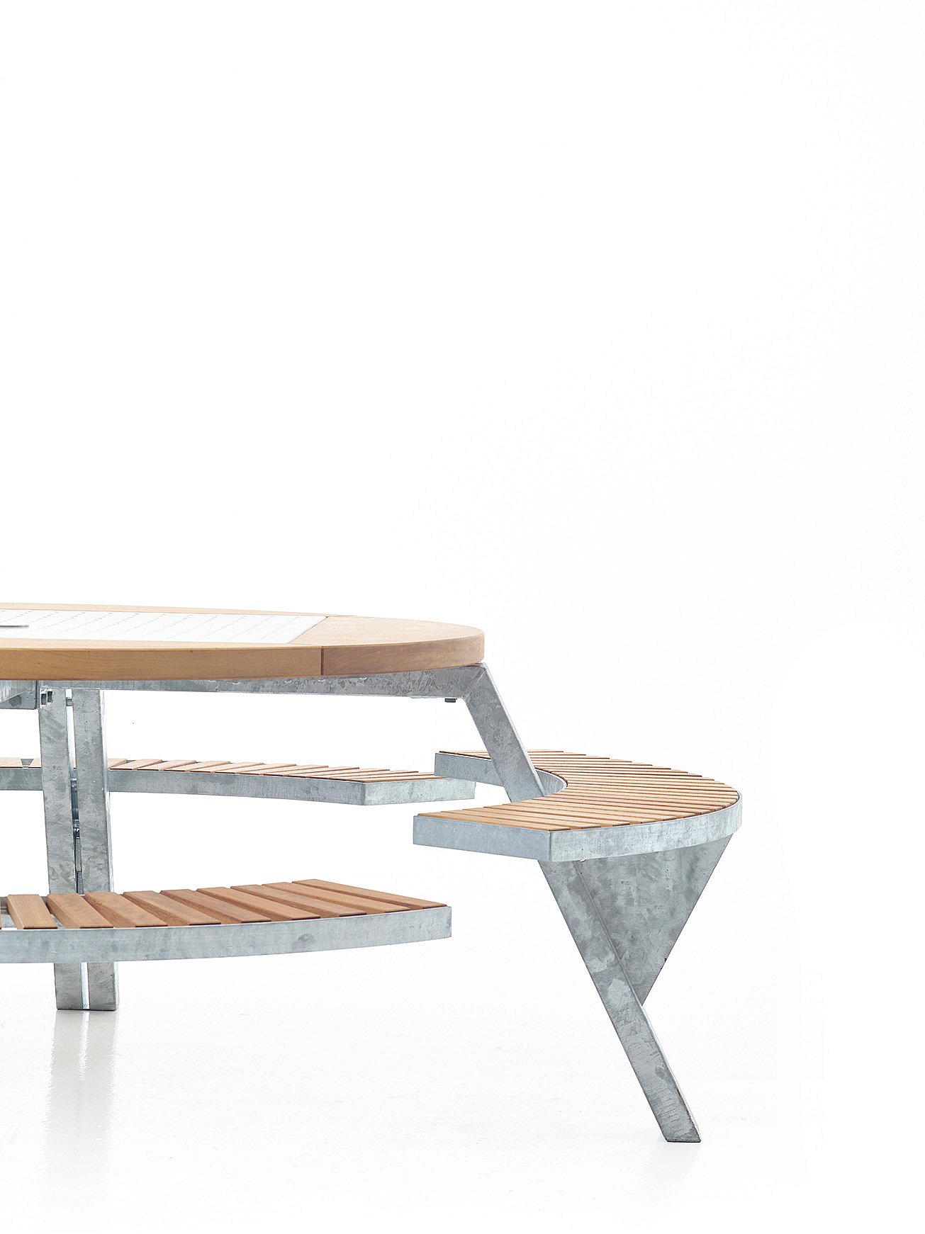   Studio close-up van de Gargantua tafel met dezelfde gebogen houten bank, verschoven naar een tweede aangepaste positie naast het gegalvaniseerde frame.