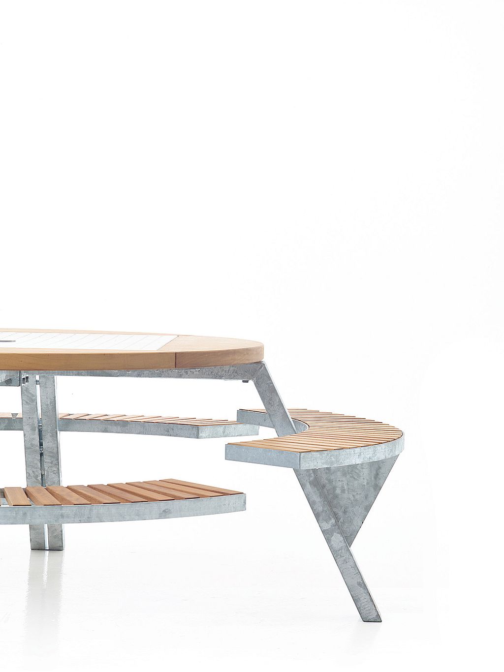 Gros plan studio de la table Gargantua montrant le même banc incurvé en bois, déplacé dans une deuxième position à côté du cadre galvanisé.