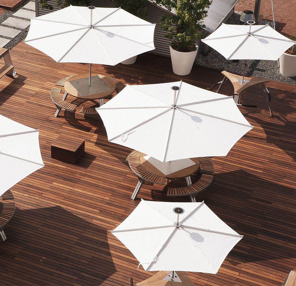 Bovenaanzicht van verschillende witte patio-inumbrina-parasols met ronde houten picknick-gargantuatafels op een groot houten dek.