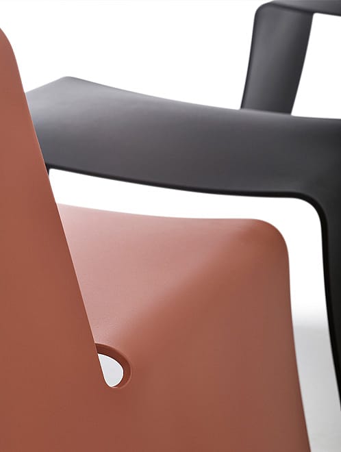 Empilement de structures métalliques de chaises ou de tabourets, de couleur rouge rouille, vert olive et bleu clair, chacune portant en relief une partie du nom Extremis.