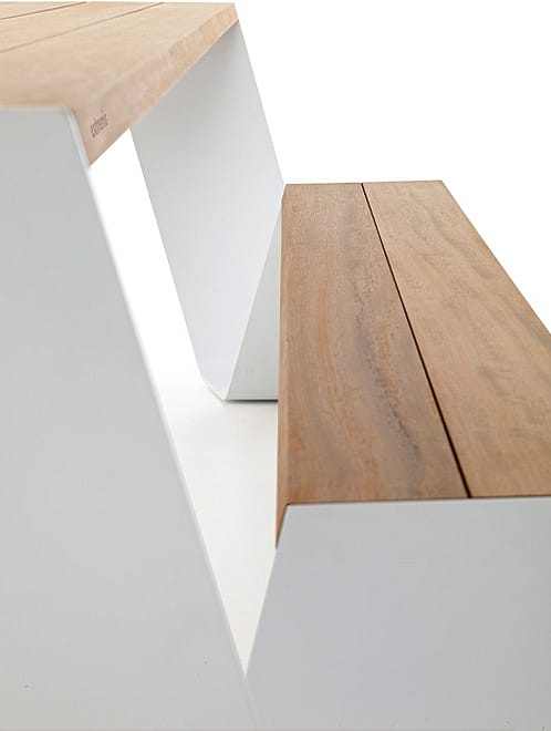 Gros plan d'une assise ou d'un plateau de table en métal couleur rouille, avec le nom Extremis discrètement embossé près de deux petits trous ronds.
