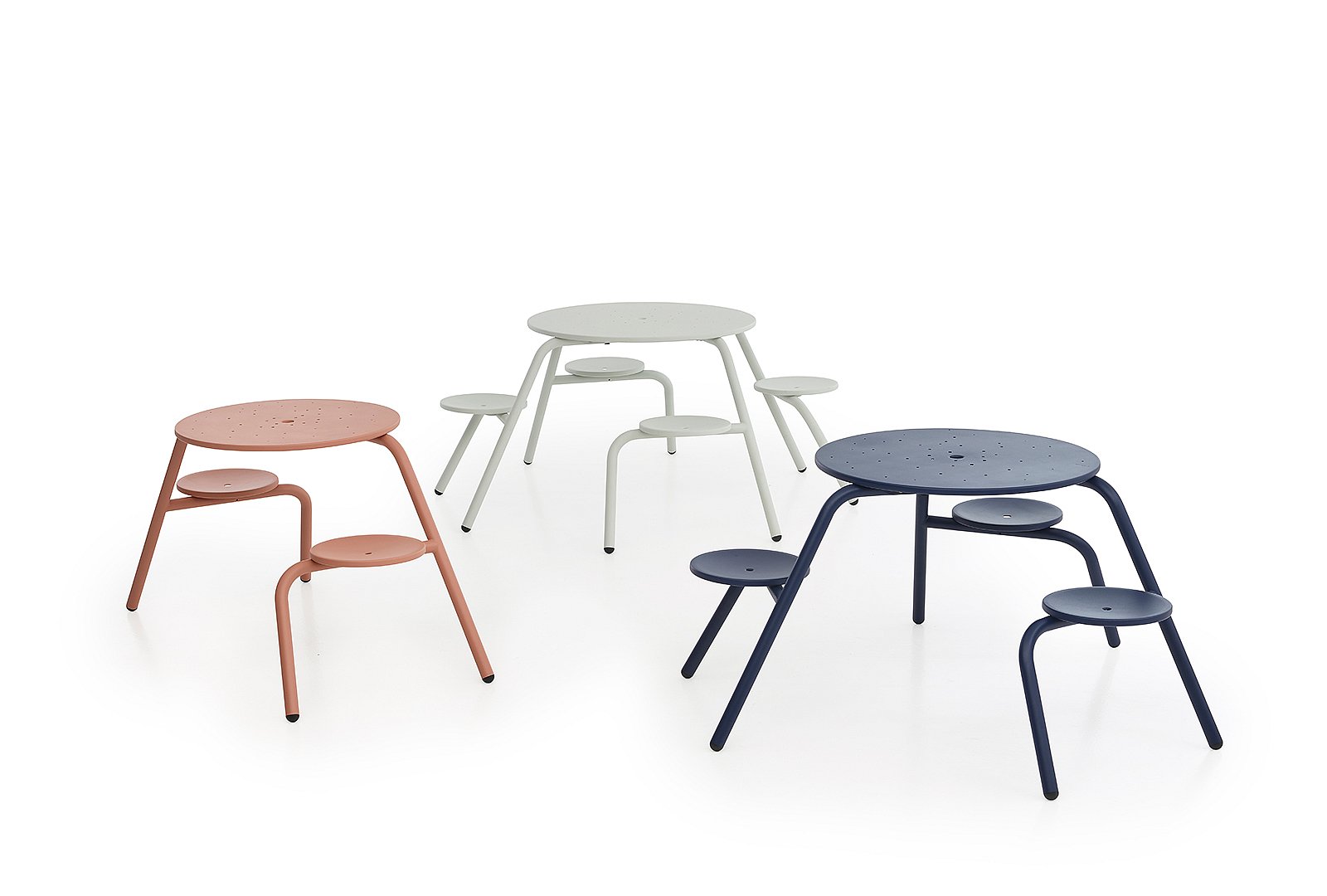 Trois tables de pique-nique rondes Virus en rose doux, blanc et bleu foncé présentées dans un décor de studio épuré, chacune avec des sièges circulaires attachés.
