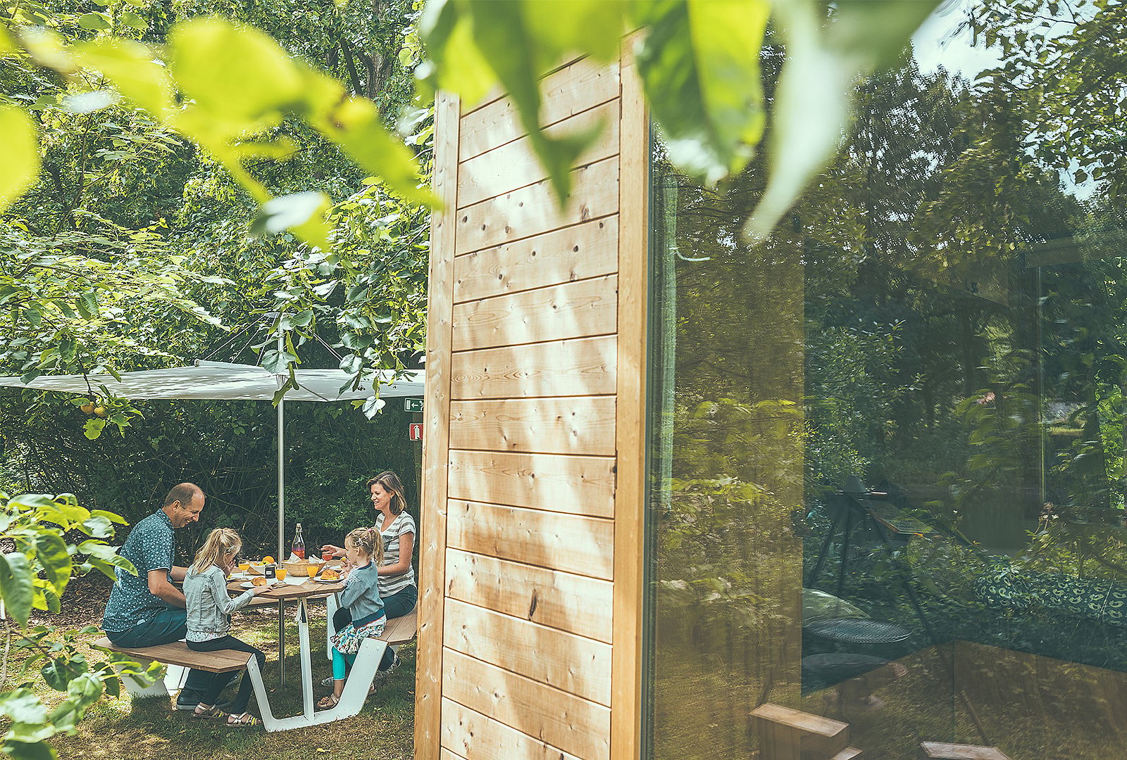 Een ander uitzicht op de Anker-picknicktafel met Inumbra-parasol, wat de beschutte eetgelegenheid in de buitenlucht versterkt.