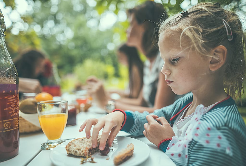Kind aan de picknicktafel in de jachthaven tijdens een buitenontbijt, met aandacht voor familie-samenhorigheid in het Pop-Up Hotel.