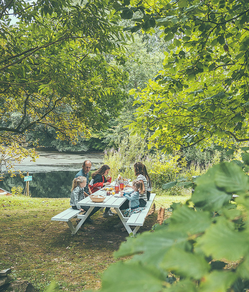 Klein huisje in glampingstijl in een bosrijke omgeving met Extremis-buitenmeubels in de buurt, die het verhaal introduceren van het vinden van rust en saamhorigheid in de natuur.