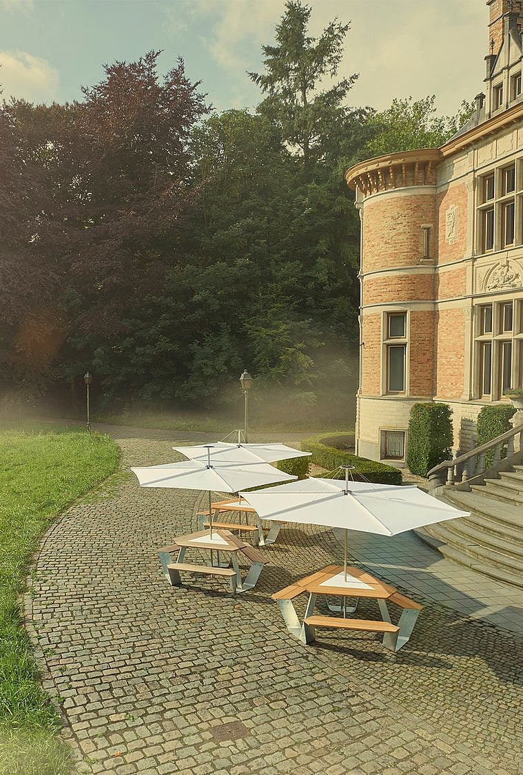 Vue des tables plus foncées avec un château en arrière-plan et couvertes de parasols inumbrina.