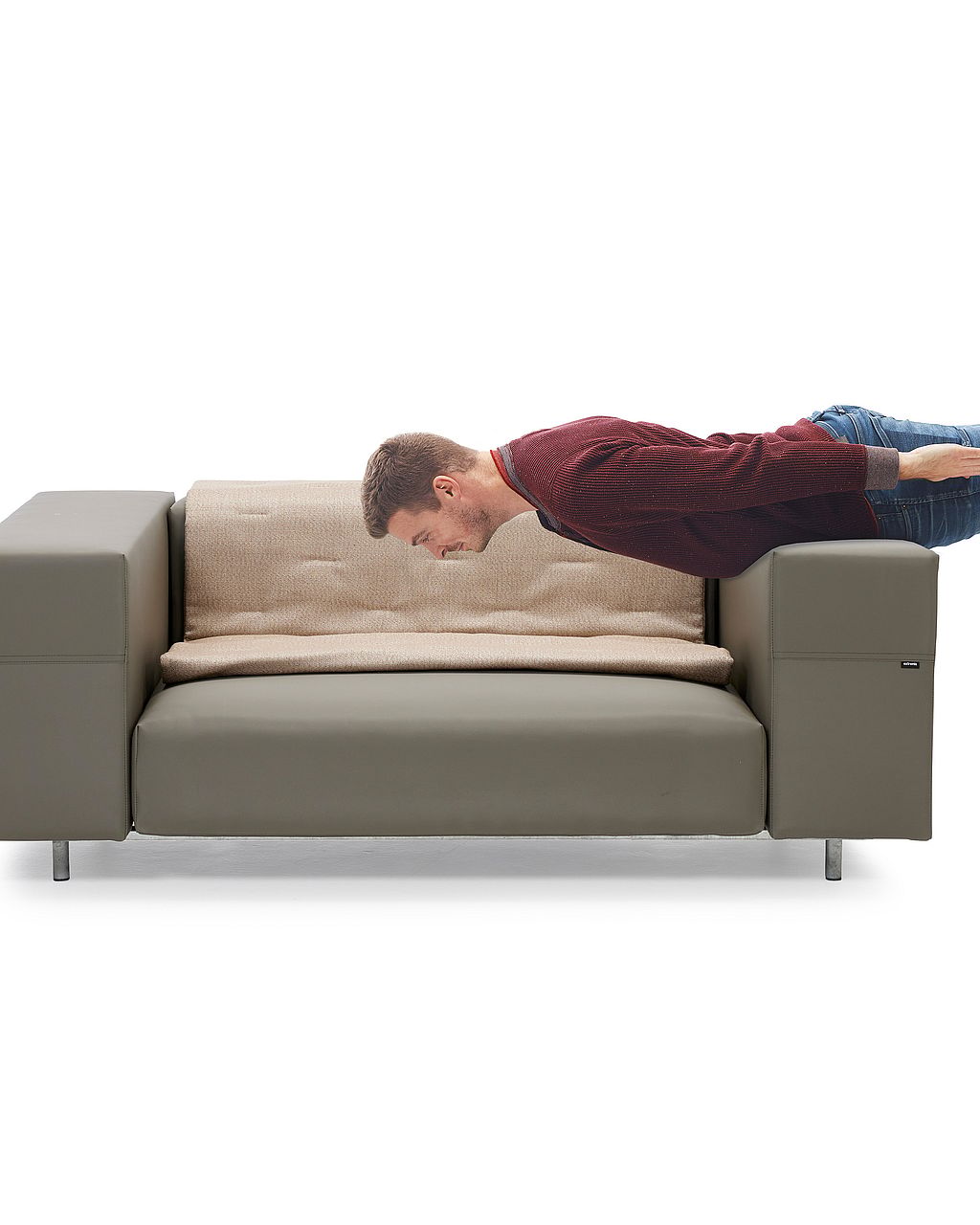 Ein Mann lehnt sich in einem Studio-Setting bäuchlings über ein Walrus-Gartensofa und demonstriert so die gepolsterte Sitzfläche und Rückenlehne.