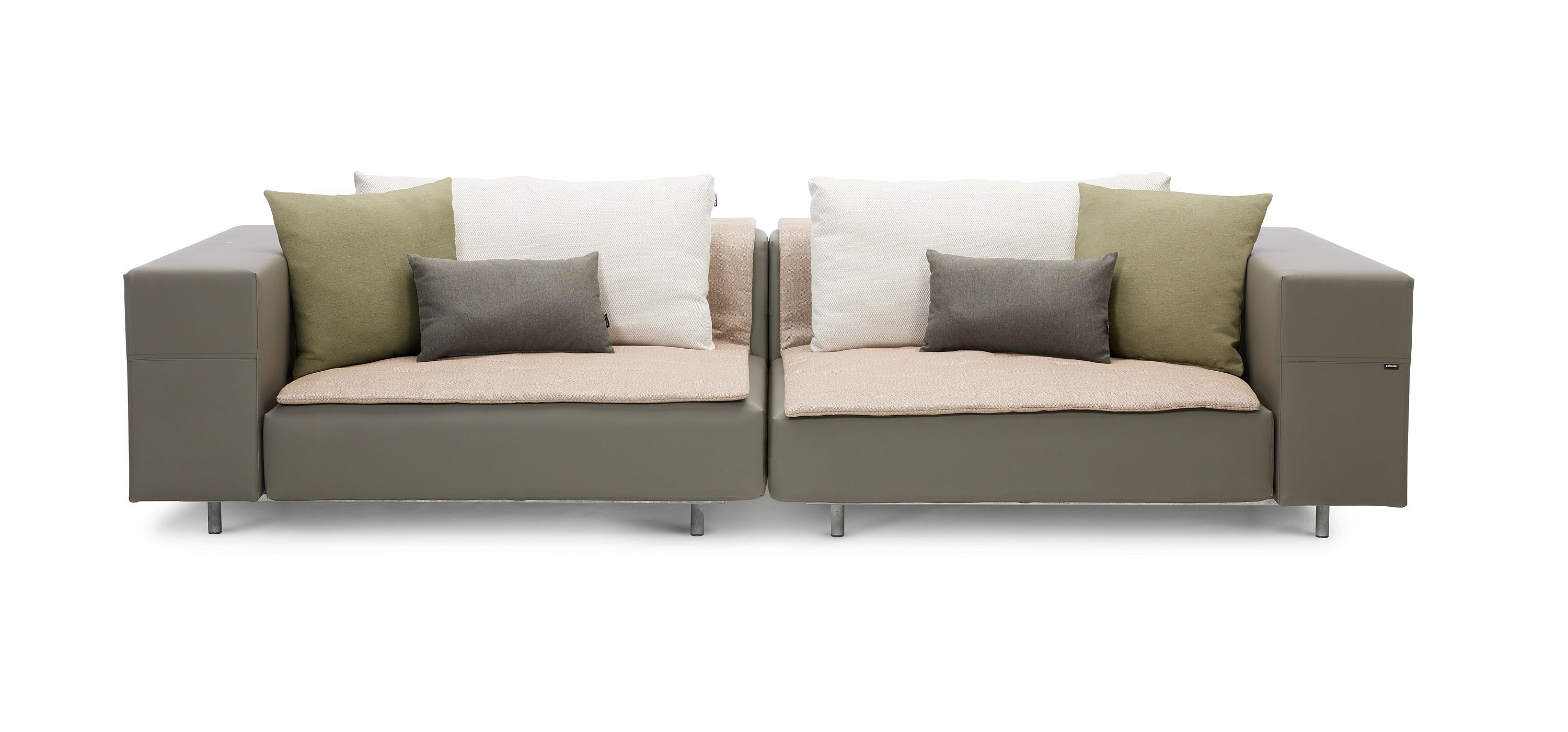   Zwei miteinander verbundene Walrus-Sofa-Module sind mit weißen Rückenkissen, hellen Sitzdecken, grünen Dekokissen und grauen Lendenkissen ausgestattet.