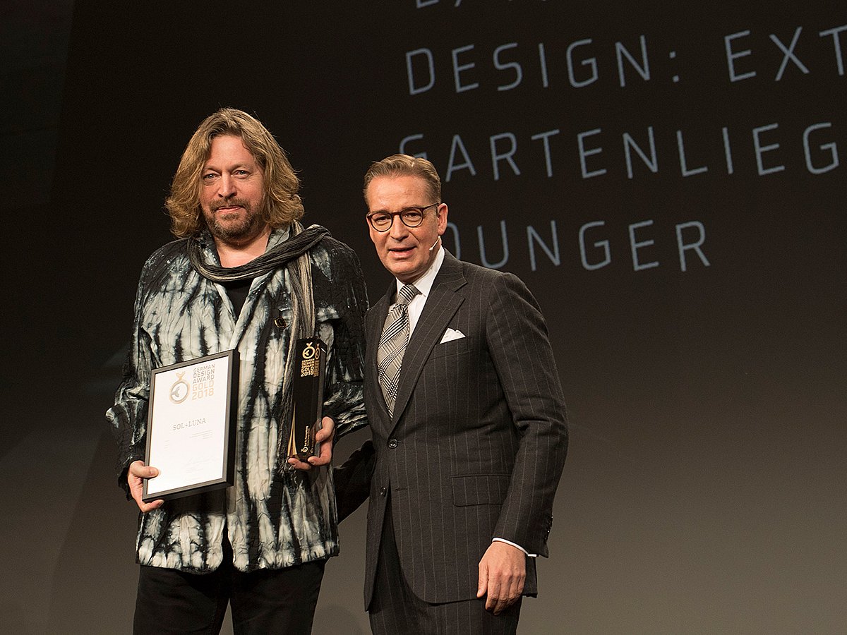 Dirk Wynants steht während der Preisverleihung in Frankfurt mit der Trophäe und Urkunde des German Design Award neben einem Mann im dunklen Anzug auf der Bühne.