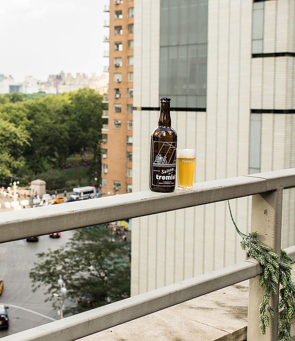 Bouteille et verre de bière Tremist placés sur la corniche du toit avec une vue panoramique sur Central Park et le rond-point en contrebas.