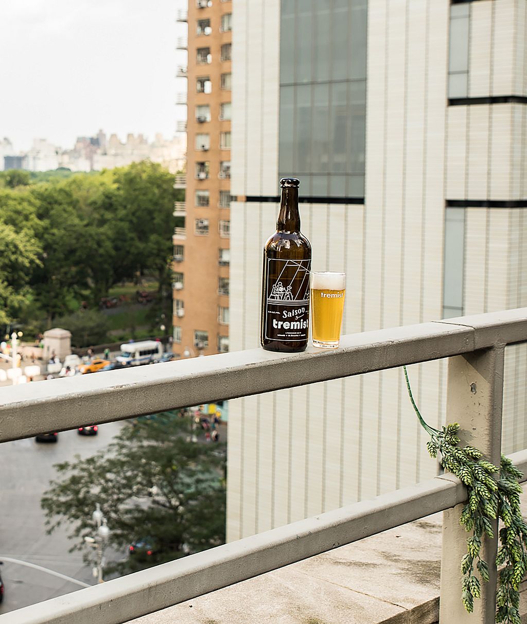 Bottle and glass of Tremist beer placed on the rooftop ledge with a sweeping view over Central Park and the traffic circle below.