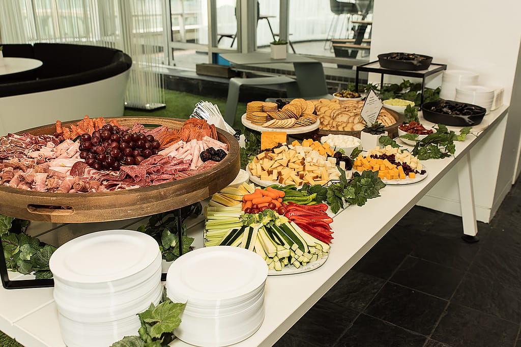 Grand buffet rempli de charcuteries, fromages, raisins, pain et légumes coupés, reflétant le thème culinaire belge de l’événement.
