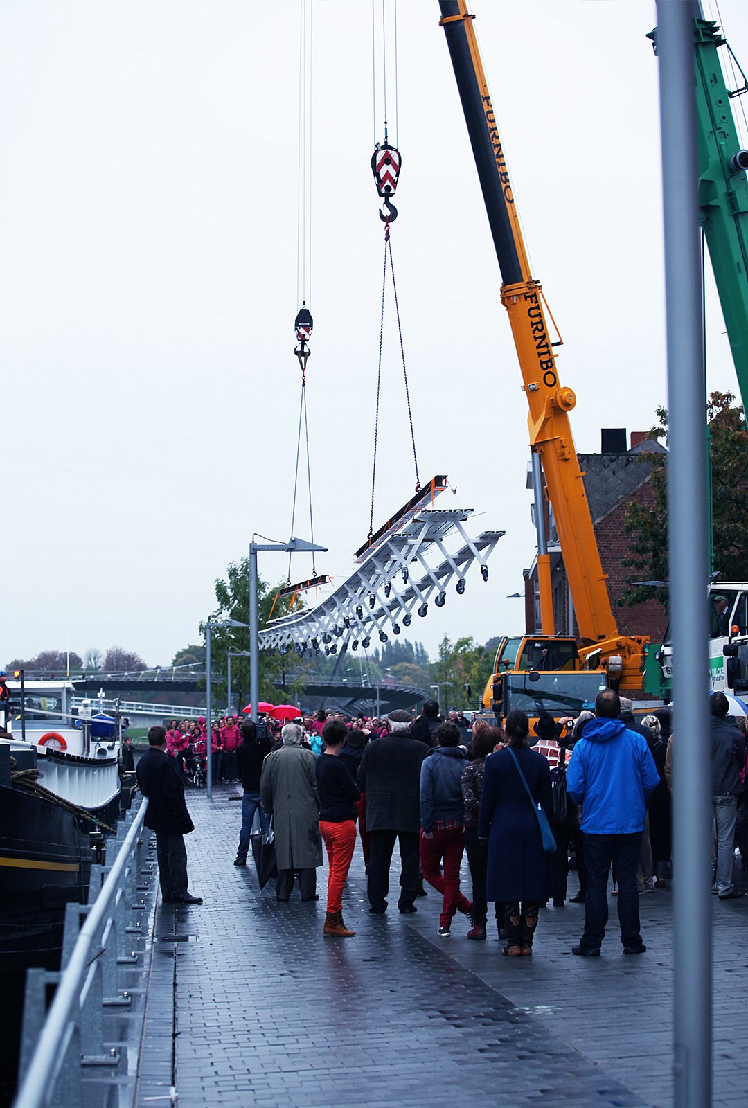 “Large group of people in bright pink jackets standing along both sides of the extra-long white table outdoors.