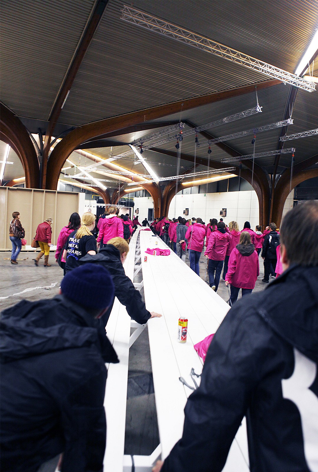 Wide indoor view of the thirty-metre table on wheels, lined with people gathered along one side.