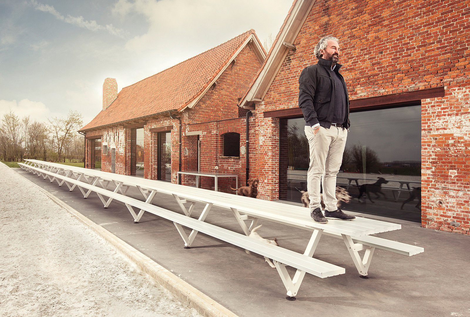 Man standing on the longest marina table in front of a brick house.