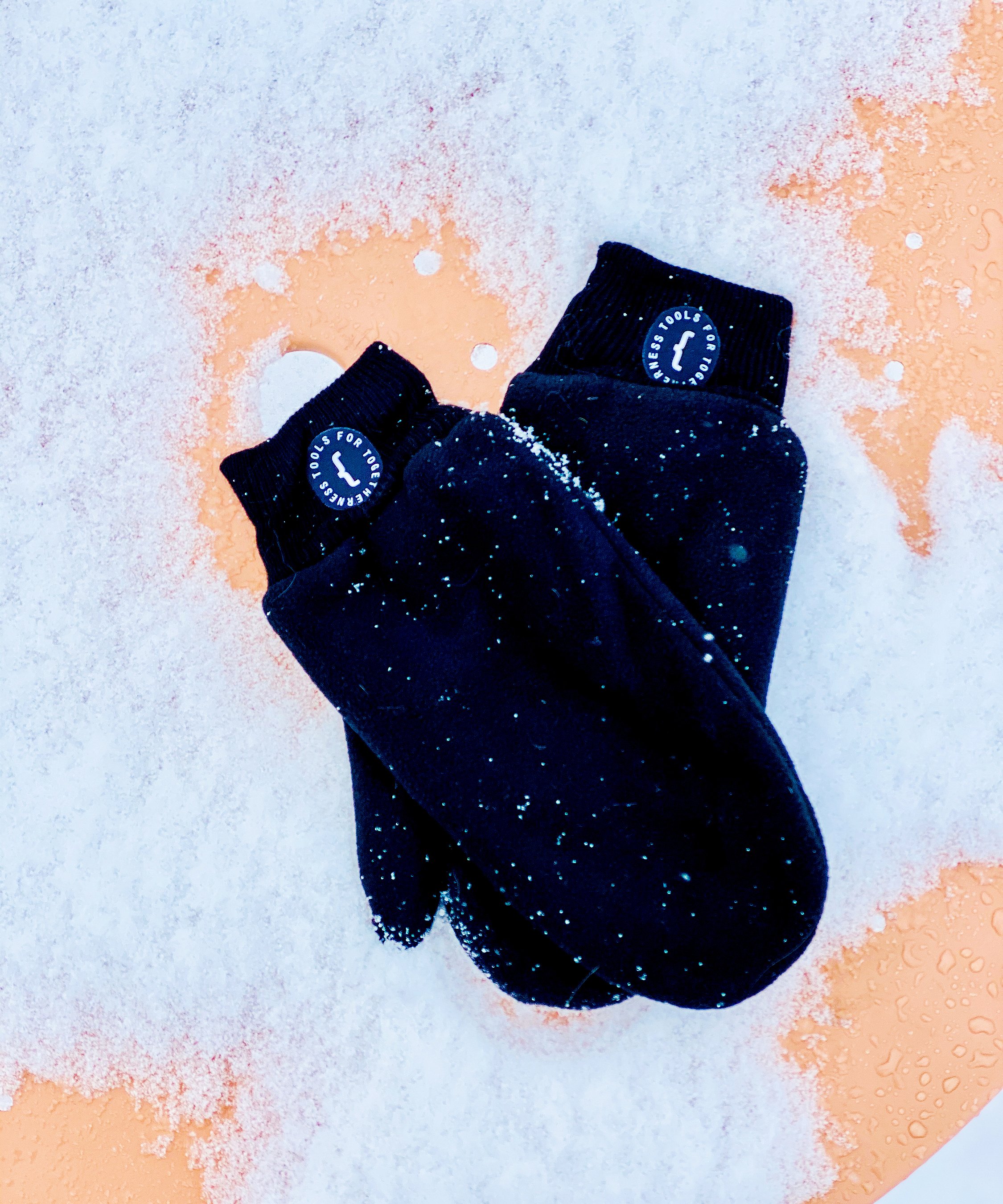 Ein Paar Extremis-Handschuhe auf einem beigen, schneebedeckten Virustisch.