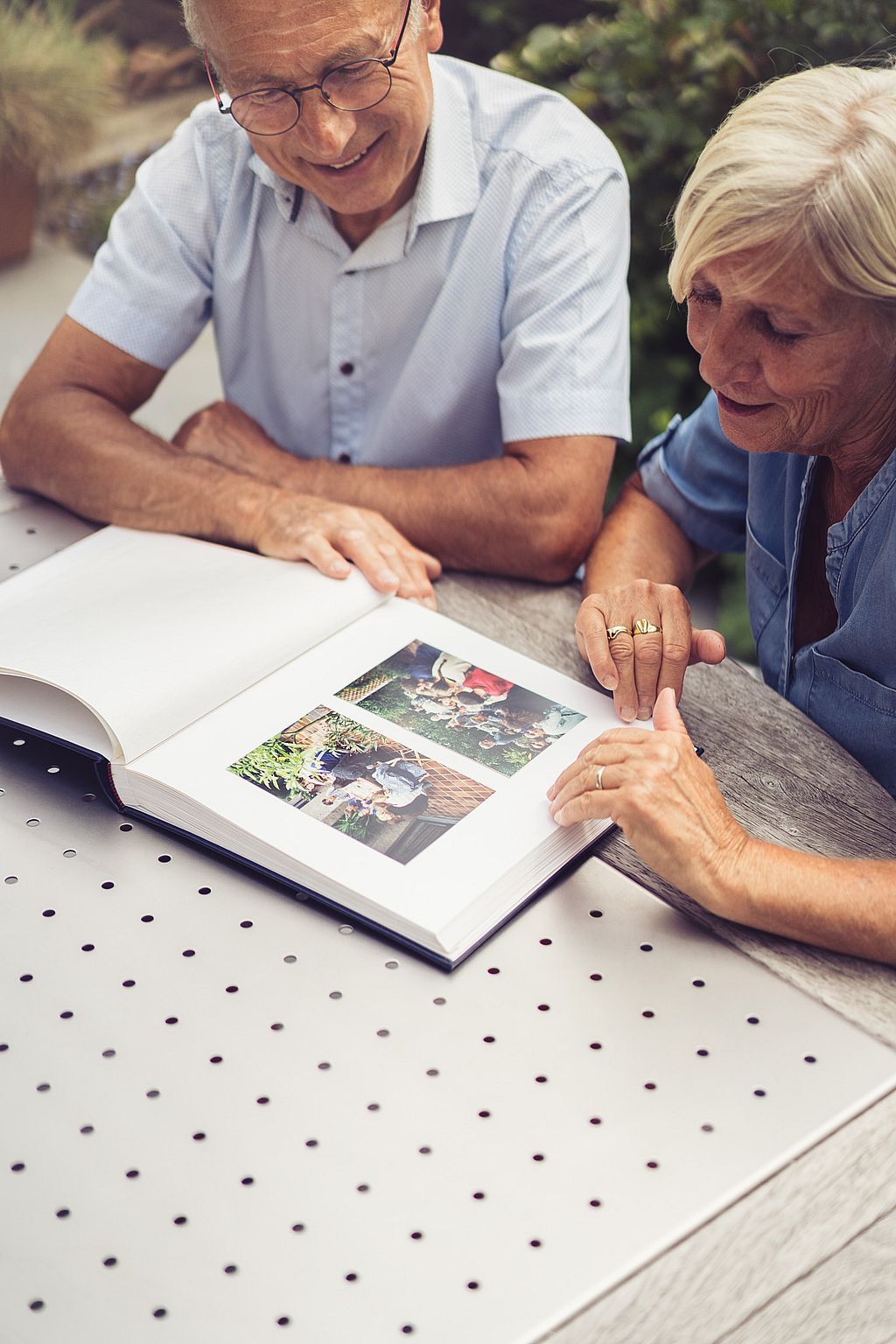 Gros plan du couple regardant un album photo sur la table de Gargantua, réfléchissant à des années de souvenirs partagés en plein air.