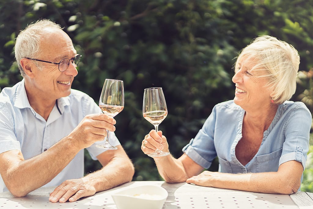 Le couple sourit et lève ses verres dans un toast à travers la table Gargantua par une belle journée d’été.